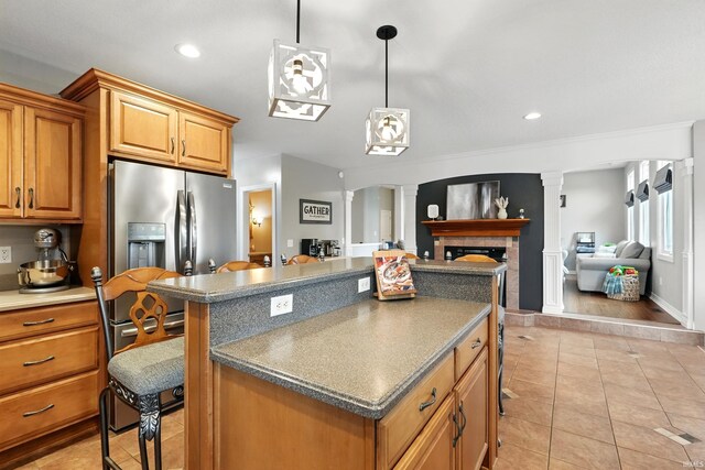 3908 County Road 4, Ashley, IN 46705 - kitchen featuring ornate columns, light tile patterned floors, stainless steel refrigerator with ice dispenser, a center island, and brown cabinetry