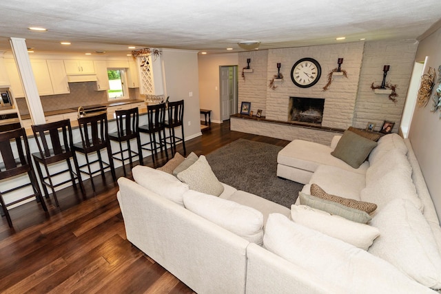 24413 Mckelvey Ave, Elkhart, IN 46516 - living area with recessed lighting, dark wood-style floors, crown molding, a fireplace, and ornate columns