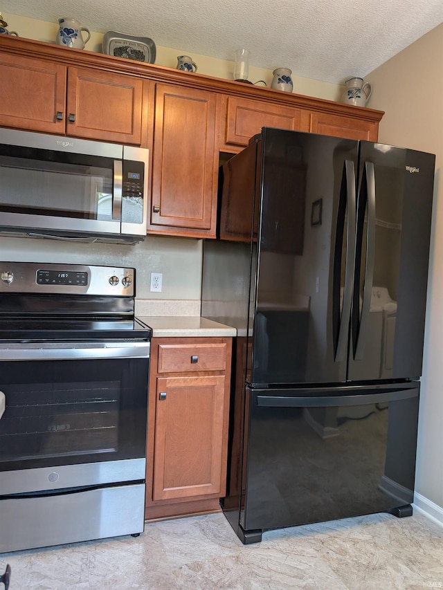 117 Blue Heron Cv, Decatur, IN 46733 - kitchen featuring appliances with stainless steel finishes, light countertops, brown cabinets, and a textured ceiling