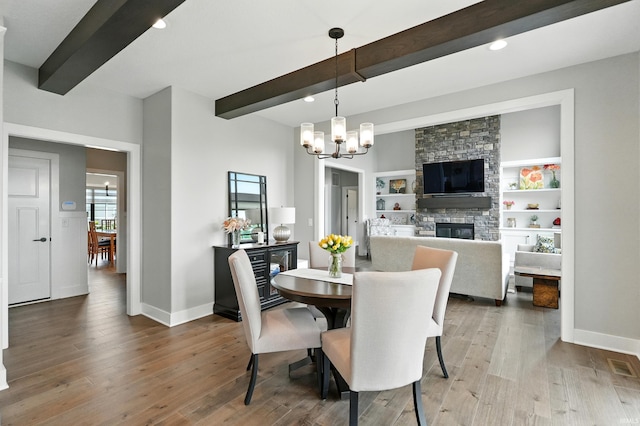 13176 Malfini Trl, Fort Wayne, IN 46845 - dining space featuring beamed ceiling, a chandelier, wood finished floors, a fireplace, and recessed lighting