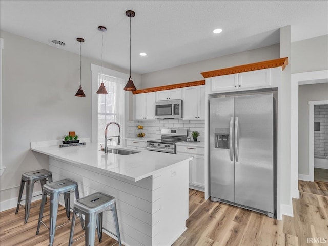 439 E Wayne St, Fort Wayne, IN 46802 - kitchen with appliances with stainless steel finishes, a breakfast bar, white cabinetry, light wood-style floors, and recessed lighting