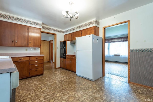 644 W Ladd Ave, Bloomington, IN 47403 - kitchen with freestanding refrigerator, black oven, a chandelier, and brown cabinetry