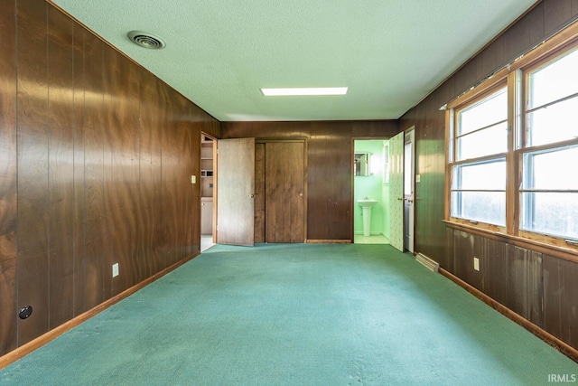 644 W Ladd Ave, Bloomington, IN 47403 - unfurnished bedroom featuring carpet floors, wooden walls, a textured ceiling, and ensuite bath
