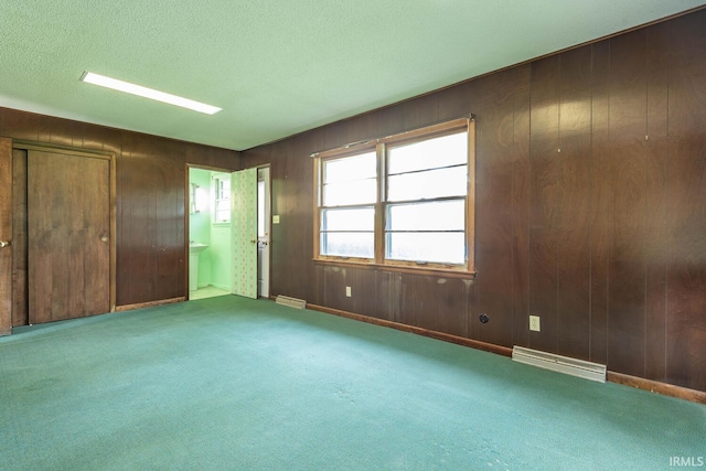 644 W Ladd Ave, Bloomington, IN 47403 - unfurnished bedroom featuring carpet floors, ensuite bath, a textured ceiling, and wooden walls
