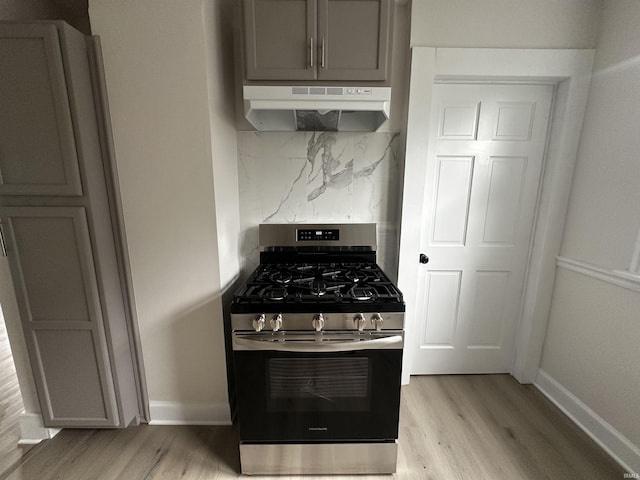 1014 E Donald St, South Bend, IN 46613 - kitchen with gas stove, under cabinet range hood, light wood-style flooring, tasteful backsplash, and gray cabinets