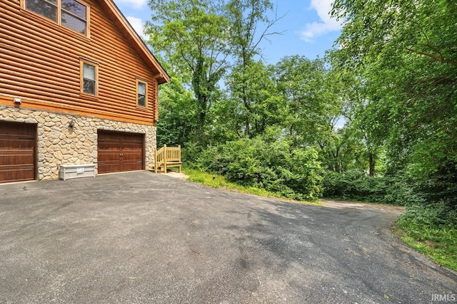 5818 Prophets Rock Rd, West Lafayette, IN 47906 - view of side of home featuring stone siding, asphalt driveway, and faux log siding