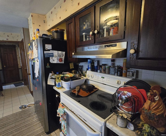 1403 Wilson St, Boonville, IN 47601 - kitchen with under cabinet range hood, electric range, light tile patterned flooring, dark brown cabinets, and glass insert cabinets