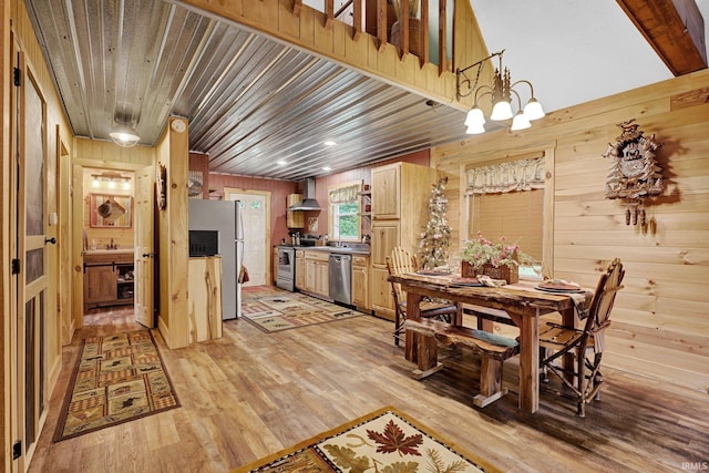 10154 W Rock E Rd, Bloomington, IN 47403 - kitchen with appliances with stainless steel finishes, wall chimney exhaust hood, wooden walls, light wood-style flooring, and a chandelier