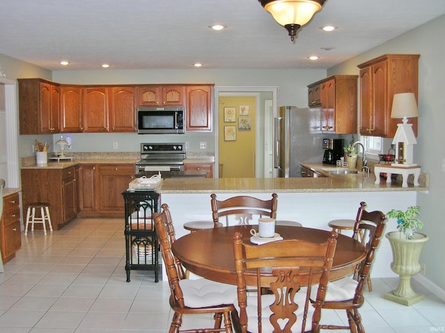 2622 Oak Trail Dr, Newburgh, IN 47630 - kitchen featuring appliances with stainless steel finishes, light tile patterned flooring, brown cabinets, a peninsula, and recessed lighting