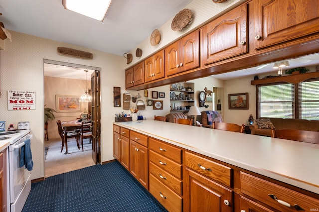 1105 N Buckeye Rd, Muncie, IN 47304 - kitchen with electric range, light countertops, carpet flooring, brown cabinetry, and wallpapered walls