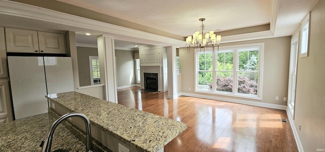 1648 S Ira St, Bloomington, IN 47401 - kitchen with freestanding refrigerator, light stone countertops, a chandelier, light wood-type flooring, and plenty of natural light