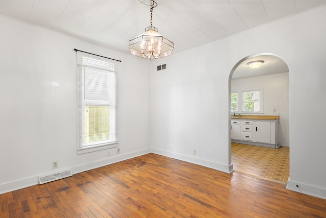 605 N 7th St, Goshen, IN 46528 - spare room featuring arched walkways, light wood-type flooring, and a chandelier