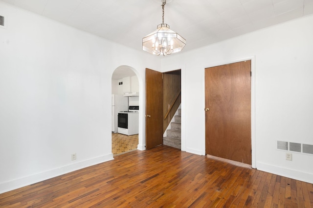605 N 7th St, Goshen, IN 46528 - spare room with arched walkways, a chandelier, stairway, and hardwood / wood-style floors