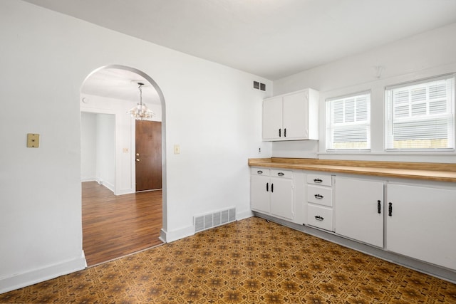 605 N 7th St, Goshen, IN 46528 - kitchen featuring arched walkways, a chandelier, white cabinets, butcher block countertops, and dark flooring