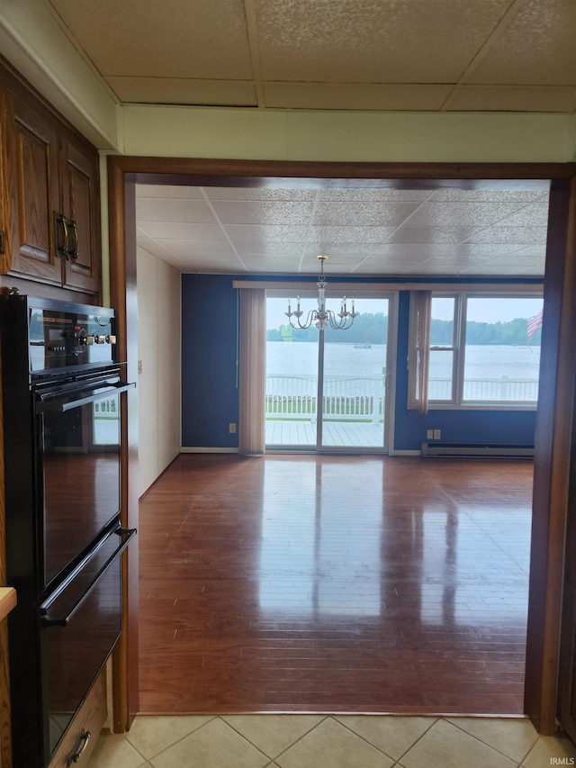 6480 E Mcguire Rd, Churubusco, IN 46723 - kitchen with a warming drawer, a baseboard radiator, a chandelier, light tile patterned floors, and a paneled ceiling