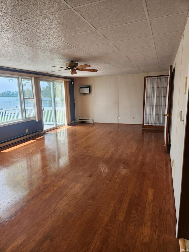 6480 E Mcguire Rd, Churubusco, IN 46723 - unfurnished room with ceiling fan, an AC wall unit, wood finished floors, a baseboard heating unit, and a drop ceiling