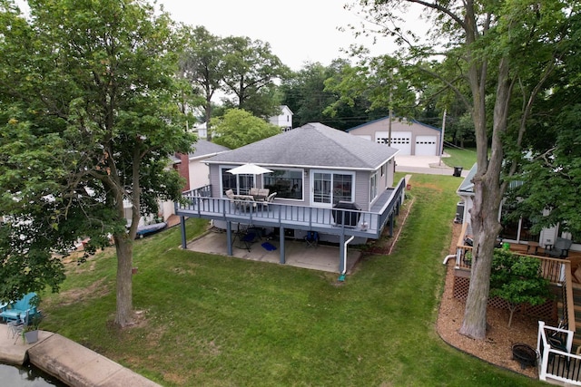 2132 Wolfs Point Dr, Rochester, IN 46975 - rear view of property featuring roof with shingles, a wooden deck, a detached garage, a lawn, and an outbuilding