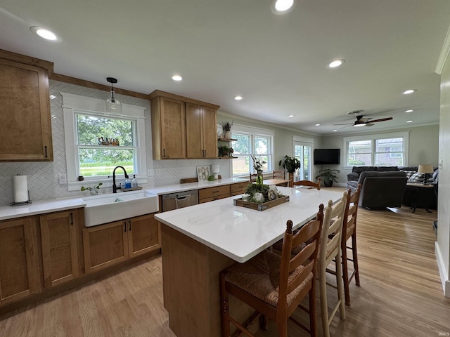 1635 Liberty St, Covington, IN 47932 - kitchen with stainless steel dishwasher, light wood finished floors, a kitchen breakfast bar, brown cabinets, and ornamental molding