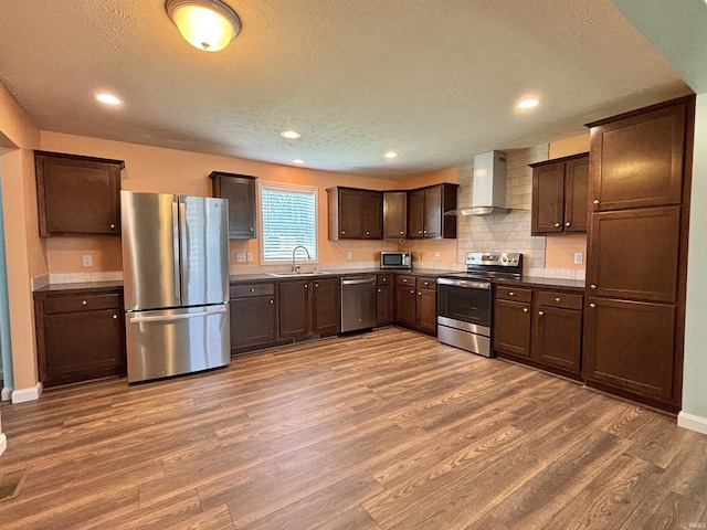 215 N Jefferson St, Lyons, IN 47443 - kitchen featuring stainless steel appliances, wall chimney exhaust hood, wood finished floors, dark brown cabinetry, and a textured ceiling