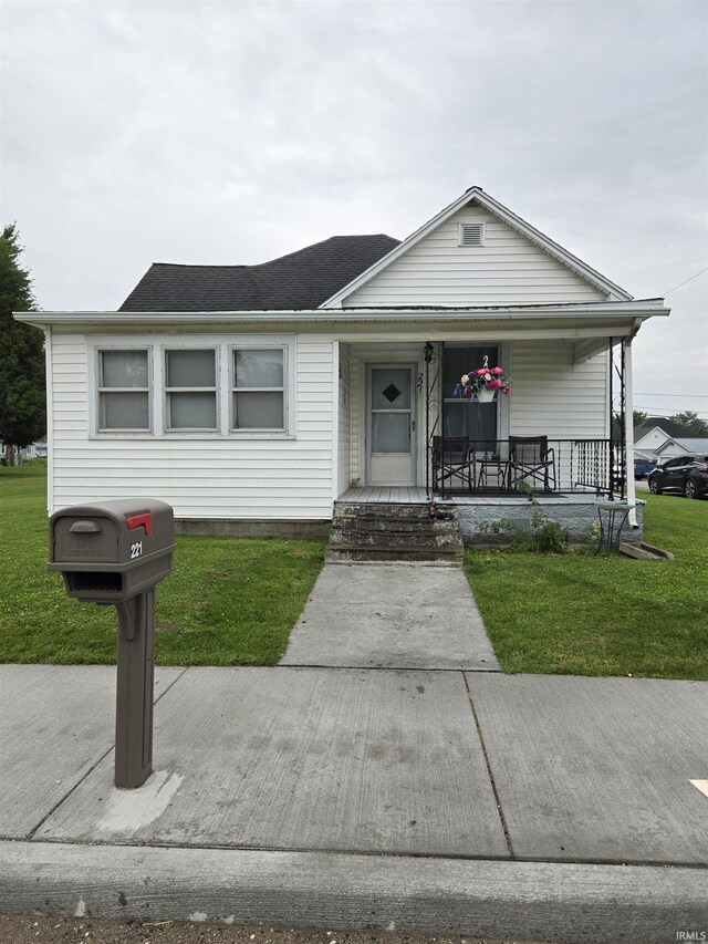221 W 11th St, Bicknell, IN 47512 - view of front of home with a front yard, covered porch, and roof with shingles