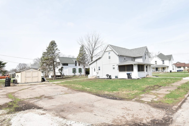 206 N Van Buren Ave, Fowler, IN 47944 - view of side of property with a storage unit, a sunroom, asphalt driveway, a lawn, and a residential view