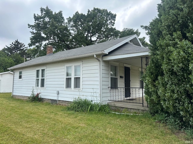237 Stanley St, Mishawaka, IN 46545 - view of side of property with a chimney, a yard, and covered porch