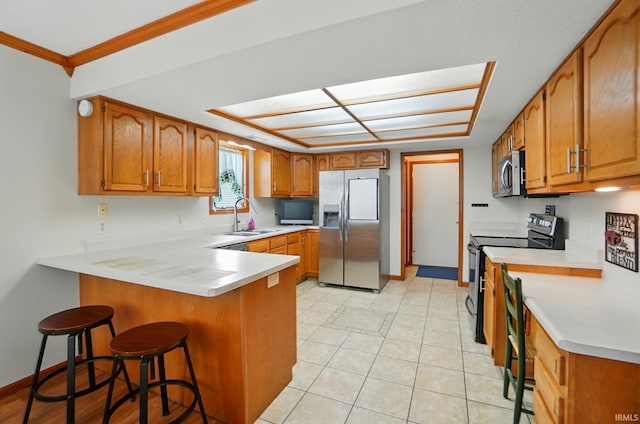 1322 Canal Ridge Dr, New Haven, IN 46774 - kitchen featuring stainless steel appliances, a peninsula, brown cabinetry, a breakfast bar area, and ornamental molding