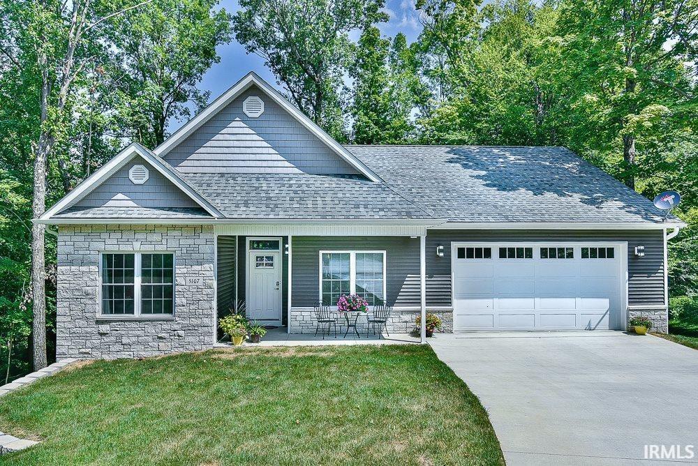 5107 Weathers Ct, Bloomington, IN 47404 - view of front of house with stone siding, an attached garage, a shingled roof, and a front lawn