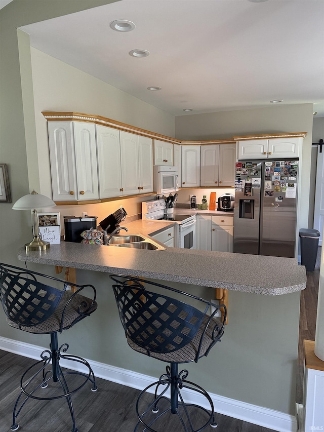 5844 Flagstone Dr, Evansville, IN 47711 - kitchen with white appliances, dark wood-type flooring, a peninsula, a breakfast bar, and recessed lighting