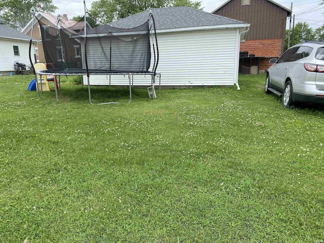 506 N Sprunger St, Berne, IN 46711 - back of house featuring a trampoline, a shingled roof, and a yard