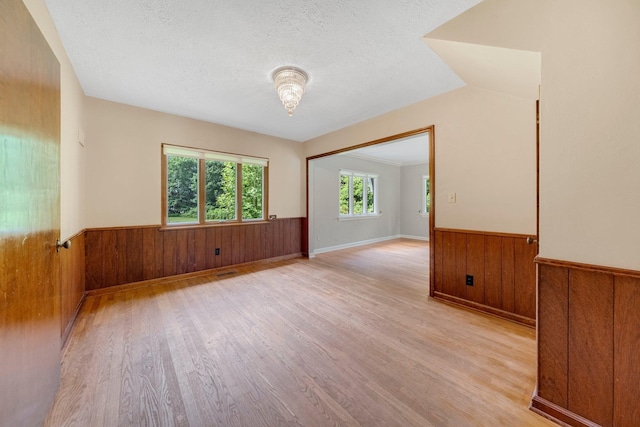 1402 Jackson Rd, South Bend, IN 46614 - spare room with wainscoting, wood walls, light wood-style flooring, and a textured ceiling
