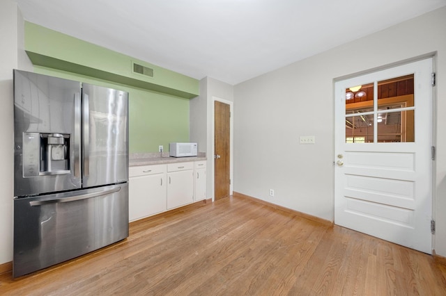 1402 Jackson Rd, South Bend, IN 46614 - kitchen featuring stainless steel fridge, white microwave, light wood-style floors, light countertops, and white cabinets
