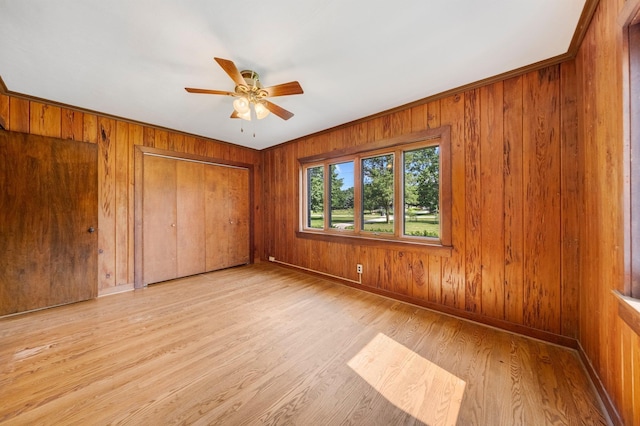 1402 Jackson Rd, South Bend, IN 46614 - unfurnished bedroom with light wood-type flooring, wooden walls, and ceiling fan