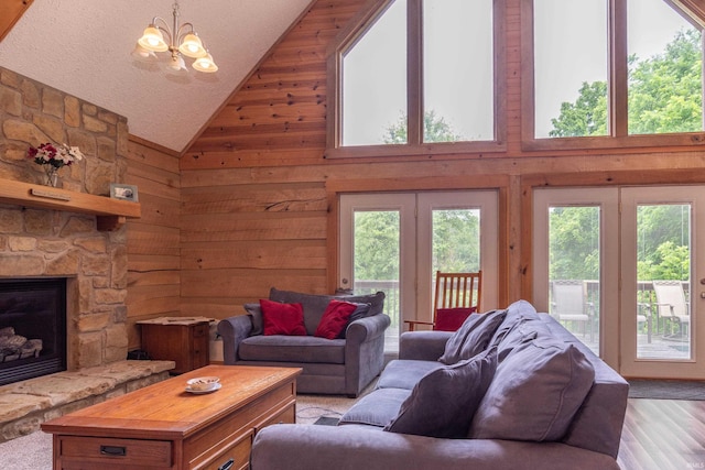 1275 N Sewell Rd, Bloomington, IN 47408 - living room featuring high vaulted ceiling, wooden walls, a chandelier, a stone fireplace, and light wood-style floors