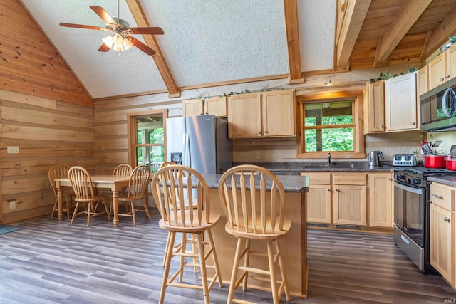 1275 N Sewell Rd, Bloomington, IN 47408 - kitchen with stainless steel appliances, dark wood-type flooring, a kitchen bar, a ceiling fan, and wooden walls