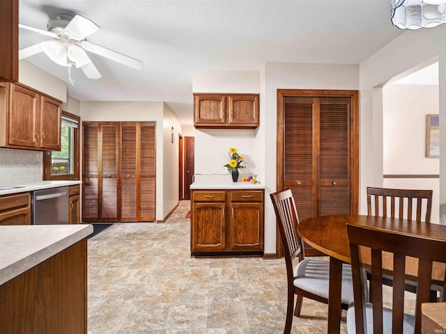 3723 Pebblewood Pl, Fort Wayne, IN 46804 - kitchen with stainless steel dishwasher, light countertops, a ceiling fan, a textured ceiling, and light stone finish floors