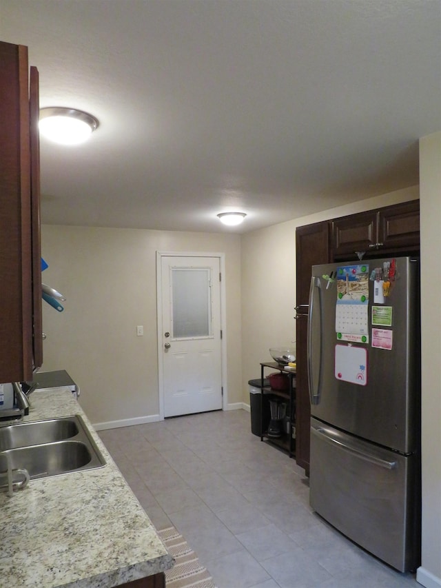 219 Fulton Ave, Rochester, IN 46975 - kitchen with freestanding refrigerator, light countertops, dark brown cabinets, and light tile patterned floors