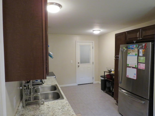 219 Fulton Ave, Rochester, IN 46975 - kitchen with freestanding refrigerator, light countertops, dark brown cabinets, and light tile patterned floors