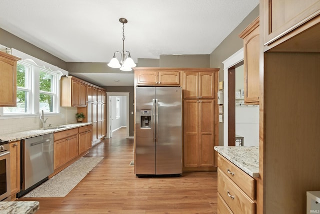319 W Wiley Ave, Bluffton, IN 46714 - kitchen with stainless steel appliances, light wood-style flooring, a chandelier, light stone countertops, and decorative light fixtures