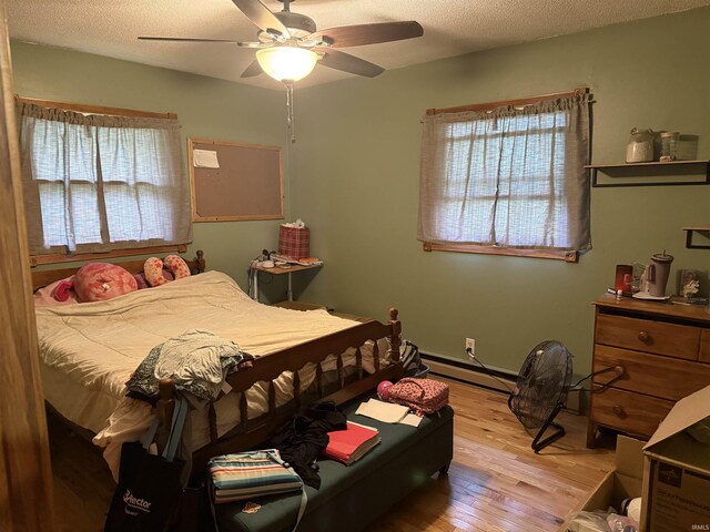 2286 N County Road 200 W, New Castle, IN 47362 - bedroom with a baseboard heating unit, light wood-style floors, a textured ceiling, and a ceiling fan