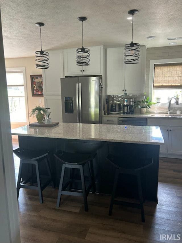 855 Reyling Dr, Jasper, IN 47546 - kitchen with stainless steel refrigerator with ice dispenser, a textured ceiling, plenty of natural light, light stone countertops, and dark wood-style flooring