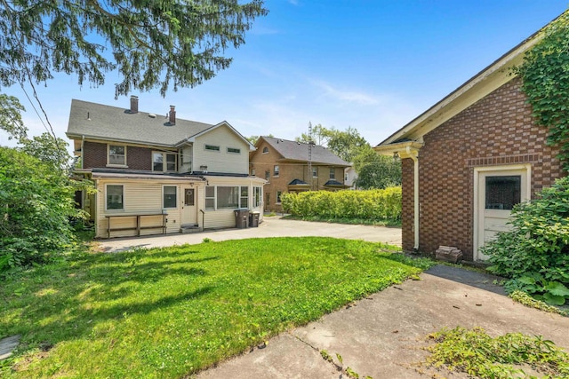 2131 Kensington Blvd, Fort Wayne, IN 46805 - back of house featuring brick siding, a patio, a lawn, a chimney, and a sunroom