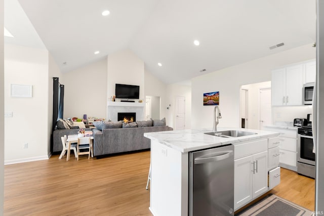 215 Mockingbird Ln, Warsaw, IN 46580 - kitchen featuring appliances with stainless steel finishes, an island with sink, white cabinetry, light wood-style floors, and open floor plan