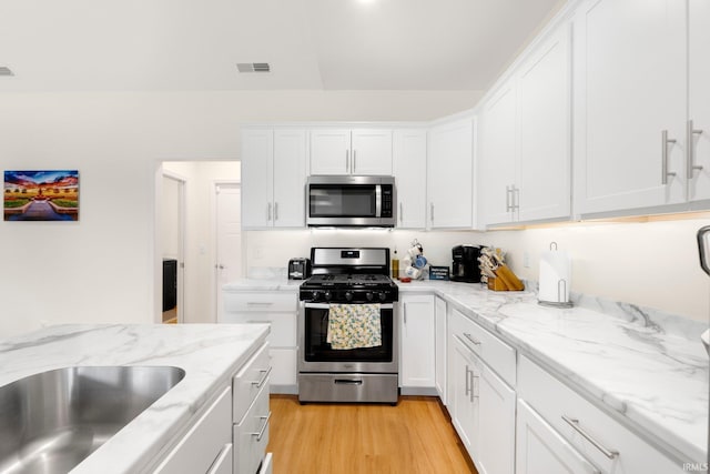 215 Mockingbird Ln, Warsaw, IN 46580 - kitchen featuring appliances with stainless steel finishes, white cabinets, light wood finished floors, and light stone countertops