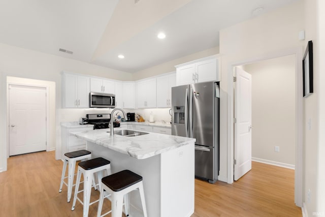 215 Mockingbird Ln, Warsaw, IN 46580 - kitchen featuring stainless steel appliances, light wood-type flooring, white cabinetry, a kitchen island with sink, and a kitchen bar