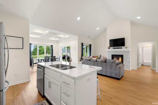 215 Mockingbird Ln, Warsaw, IN 46580 - kitchen featuring stainless steel dishwasher, freestanding refrigerator, an island with sink, light wood-style flooring, and a fireplace