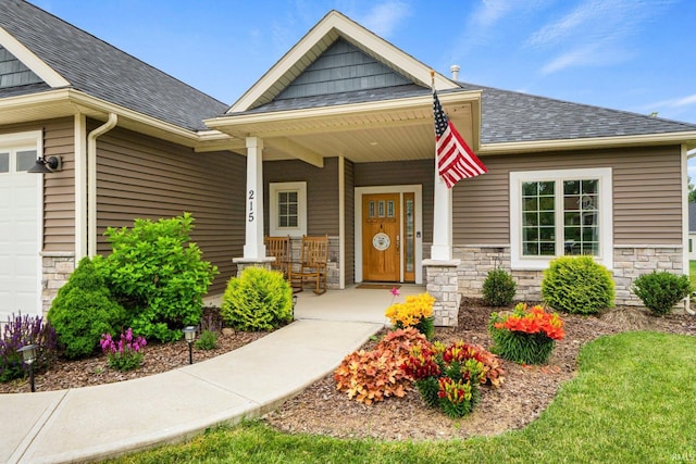 215 Mockingbird Ln, Warsaw, IN 46580 - view of exterior entry with covered porch, a shingled roof, stone siding, and a garage