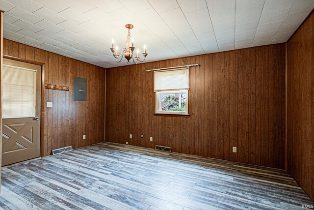 6412 E Oak St, Evansville, IN 47715 - empty room featuring a chandelier, wood finished floors, wooden walls, and electric panel