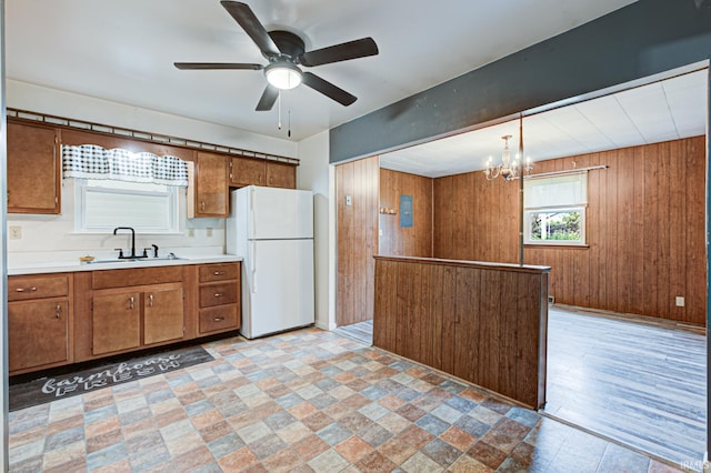 6412 E Oak St, Evansville, IN 47715 - kitchen with freestanding refrigerator, brown cabinetry, a chandelier, light countertops, and wood walls