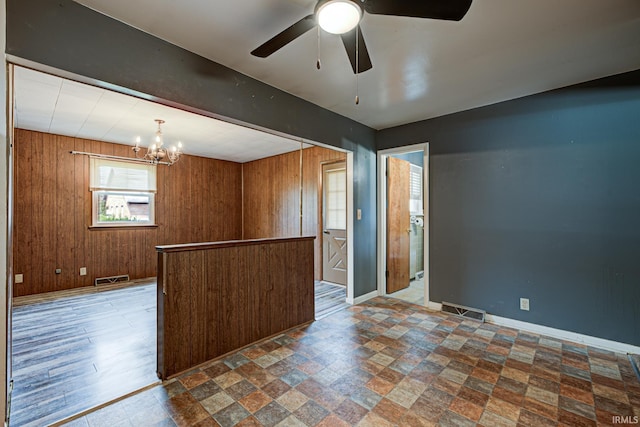6412 E Oak St, Evansville, IN 47715 - empty room featuring a chandelier, a ceiling fan, stone finish floors, and wooden walls